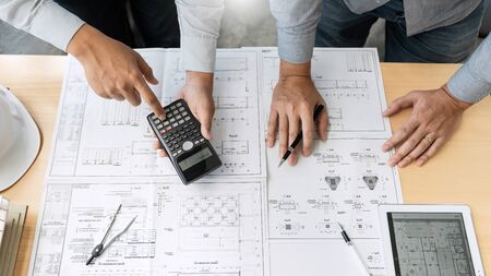 Confident engineer team working with Blue Print with architect equipment discussing and Planning work flow construction project. with partner at the table in office work site.の写真素材