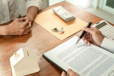 Businessman signs contract behind home architectural model Discussion with a real estate agent rental company staff  at the office property appraisal and valuation conceptの写真素材