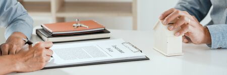 broker agent and customer holding pen, the policyholder and explain discussing for concerning mortgage loan offer for and house insuranceの写真素材