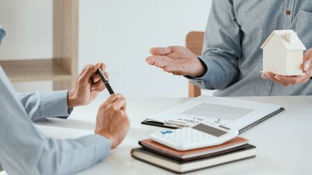 broker agent and customer holding pen, the policyholder and explain discussing for concerning mortgage loan offer for and house insuranceの写真素材
