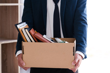 Businessmen are holding resignation document and packing personal company on brown cardboard box...