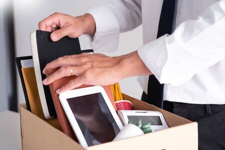 Sad Fired Young Employee businessmen hold boxes including pot plant and documents for personal belongings unemployment, resigned conceptの写真素材