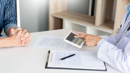Technology in medicine and health care, Doctor consultation Discussing Records with the patient by using digital tablet in doctors office.の写真素材