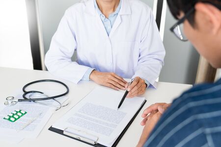 doctor working with patient taking notes with clipboard and discussing something in his medical office, health care and people conceptの写真素材