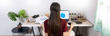 Attractive young beautiful asian woman Entrepreneur or freelancer working at home with laptop business reports and online communications on living room sofa, working remotely access conceptの写真素材