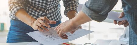 engineer Hand Drawing Plan On Blue Print with architect equipment discussing the floor plans over blueprint architectural plans at table in a modern officeの写真素材