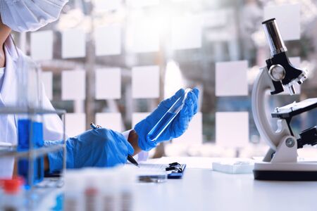 scientists researching in laboratory in white lab coat, gloves analysing, looking at test tubes sample, biotechnology concept.の写真素材