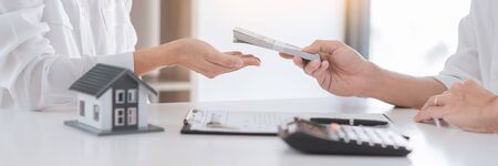 Real Estate concept, Agent with calculator for present price for loan house for investment documents and calculating table payment to customerの写真素材