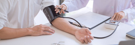 Doctor using sphygmomanometer or tonometer measuring blood pressure to a patient examined the heartbeat and talked about health care in the hospitalの写真素材