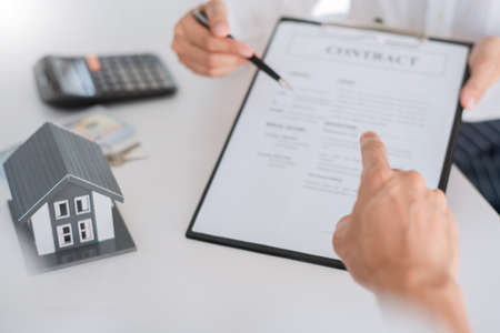 Attractive young beautiful asian woman working with laptop and document talking smartphone at the indoors living room office as a freelancer, e-coaching working, remotely or work from home conceptの写真素材