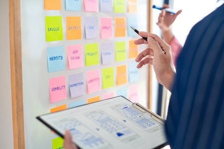 Attractive young beautiful asian woman working with laptop and document talking smartphone at the indoors living room office as a freelancer, e-coaching working, remotely or work from home conceptの写真素材