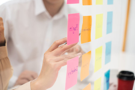 Creative group of business people brainstorming use sticky notes to share idea on glass window or...