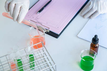 Scientist wear lab coat and protective wear are working with research or doing investigations with test tubes in experiment, Laboratory and development concept.の写真素材