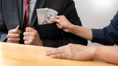 Businessman reciving money United States Dollars bills to corruption from his partner in business at working desk - bribery conceptの写真素材