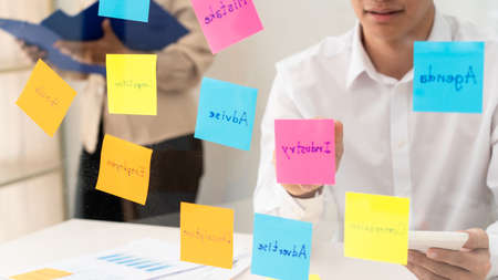 Creative group of business people brainstorming use sticky notes to share idea on glass window or table in officeの写真素材
