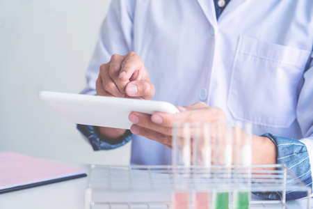 Scientist wear lab coat and protective wear are working with research or doing investigations with test tubes in experiment, Laboratory and development concept.の写真素材