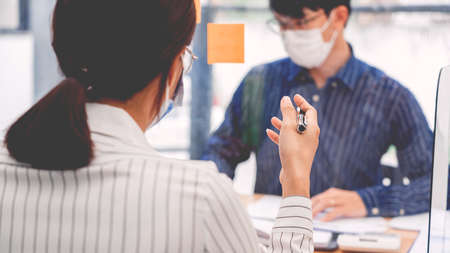 business team brainstorm they are working hard by looking through the plastic protective wall, concept of social distancing to prevent the spread of coronavirus COVID-19の写真素材