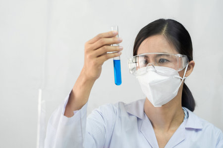 scientists researching in laboratory in white lab coat, gloves analysing, looking at test tubes...