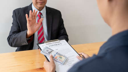 Confident businessman manager rejecting an offer of money to agreement contract from partner or refusing to take bribe, Bribery and corruption conceptの写真素材