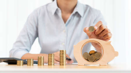 woman hand putting money coin into piggy bank with step of growing stack coins for saving money for future investment concept.の写真素材