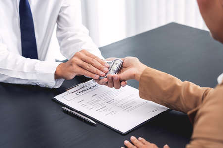 Businessmen give money to bribe partner secretly passing money, bribery and corruption conceptsの写真素材