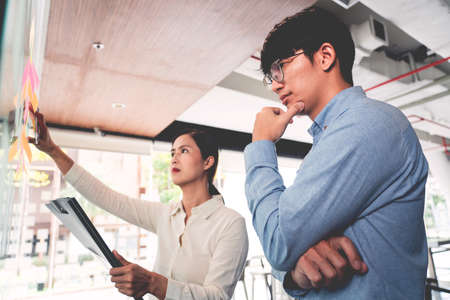 Business manager showing idea for her team and stick many memo paper on glass window to success working in business meeting  creative office, planning and management conceptの写真素材