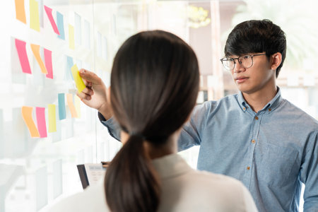 Business manager showing idea for her team and stick many memo paper on glass window to success working in business meeting  creative office, planning and management conceptの写真素材