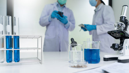 Attractive young scientist team in lab coat and safety goggles working with analysing test trial or...