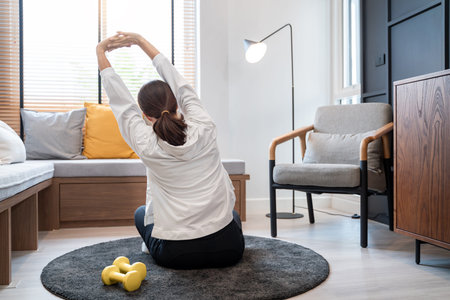 Attractive and healthy young Asian woman doing exercising at home during workout in comfy clothes on...