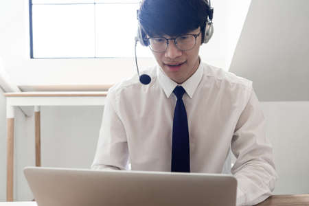 young confident male call center operator customer service representative doing his job on the phone with headsetの写真素材