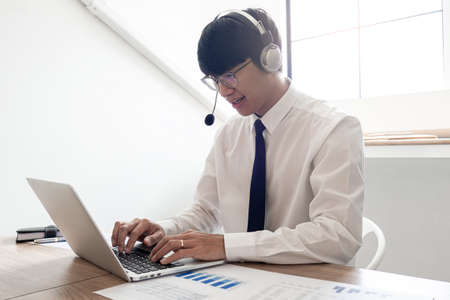 young confident male call center operator customer service representative doing his job on the phone with headsetの写真素材