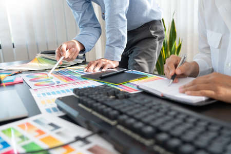 Graphic designer or creative working together coloring using graphics tablet and a stylus at desk with colleagueの写真素材