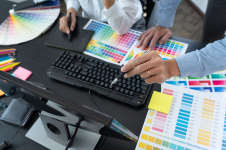 Graphic designer or creative working together coloring using graphics tablet and a stylus at desk...