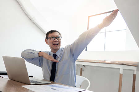 Senior handsome businessman happy and excited doing winner gesture with arms raised after Complete task of project, Cheerful positive excited careless peacefulの写真素材