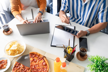 group of business people talking about project and prepare pizza and potato chips for having lunch in corporate together in officeの写真素材