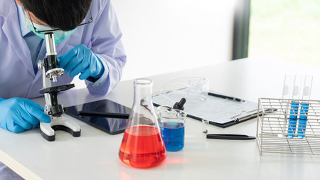 Young Asian scientist Working looking through a microscope doing research for analyzing a...