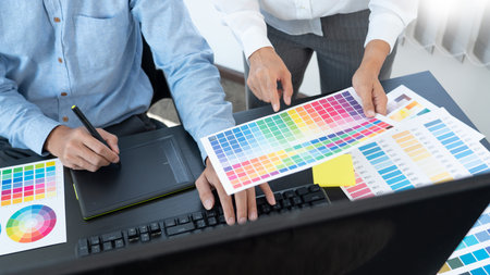 Graphic designer or creative working together coloring using graphics tablet and a stylus at desk with colleagueの写真素材