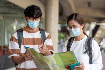 Travel, man and woman are reading paper map. wearing mask, carry backpacks. stripped shirt and...