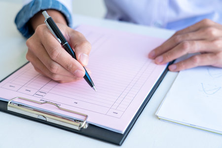 business man works on the table holds pen in right hand and write data in the table chart, wear a...