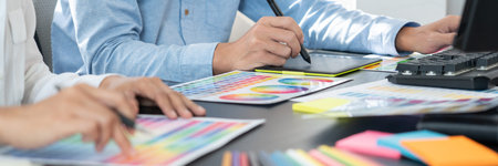 Graphic designer or creative working together coloring using graphics tablet and a stylus at desk...