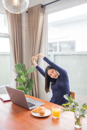 Work from home concept a female entrepreneur being relaxed stretching her arms while working remotely in her house.の写真素材