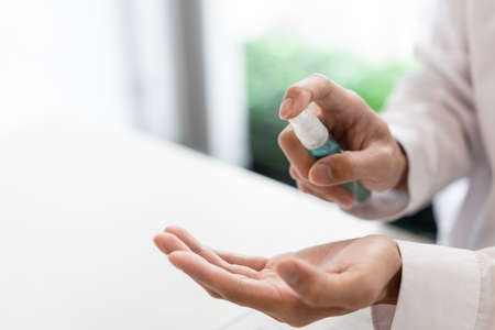 a male freelancer using alcohol rubbing his hands preventing the germ while working with others.の写真素材