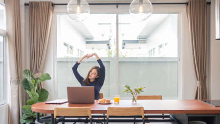 Work from home concept a female entrepreneur being relaxed stretching her arms while working remotely in her house.の写真素材