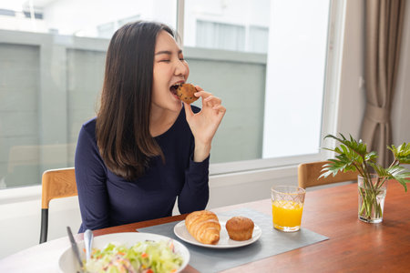 Having meal concept a young woman eating a cupcake as a dessert with orange juice after eating salad at her place.の写真素材