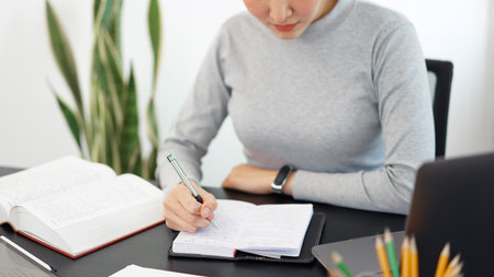 Office work concept a female secretary writing some information into a notebook eagerly.の写真素材