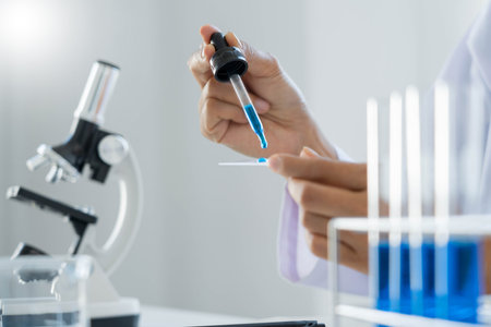 scientists researching in laboratory in white lab coat, gloves analysing, looking at test tubes...