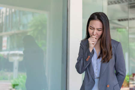 Working woman concept a working woman coughing after contacting with many people while working without any protection.の写真素材
