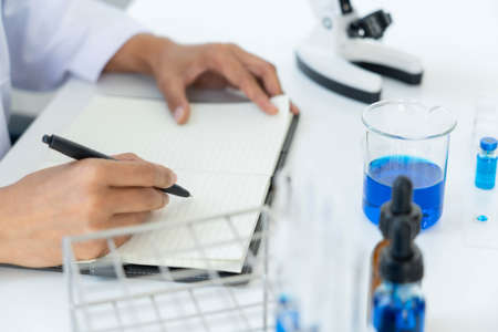 scientists researching in laboratory in white lab coat, gloves analysing, looking at test tubes sample, biotechnology concept.の写真素材