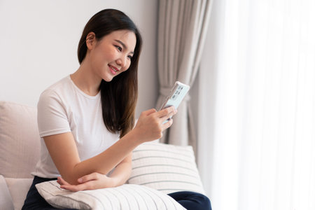 Living room concept a pretty girl sitting on the comfortable sofa spending her leisure on online...