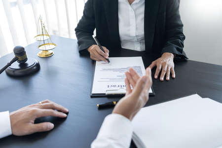 law,libra scale and hammer on the table, 2 lawyers are discussing about contract paper, law matters determination, open hand.の写真素材
